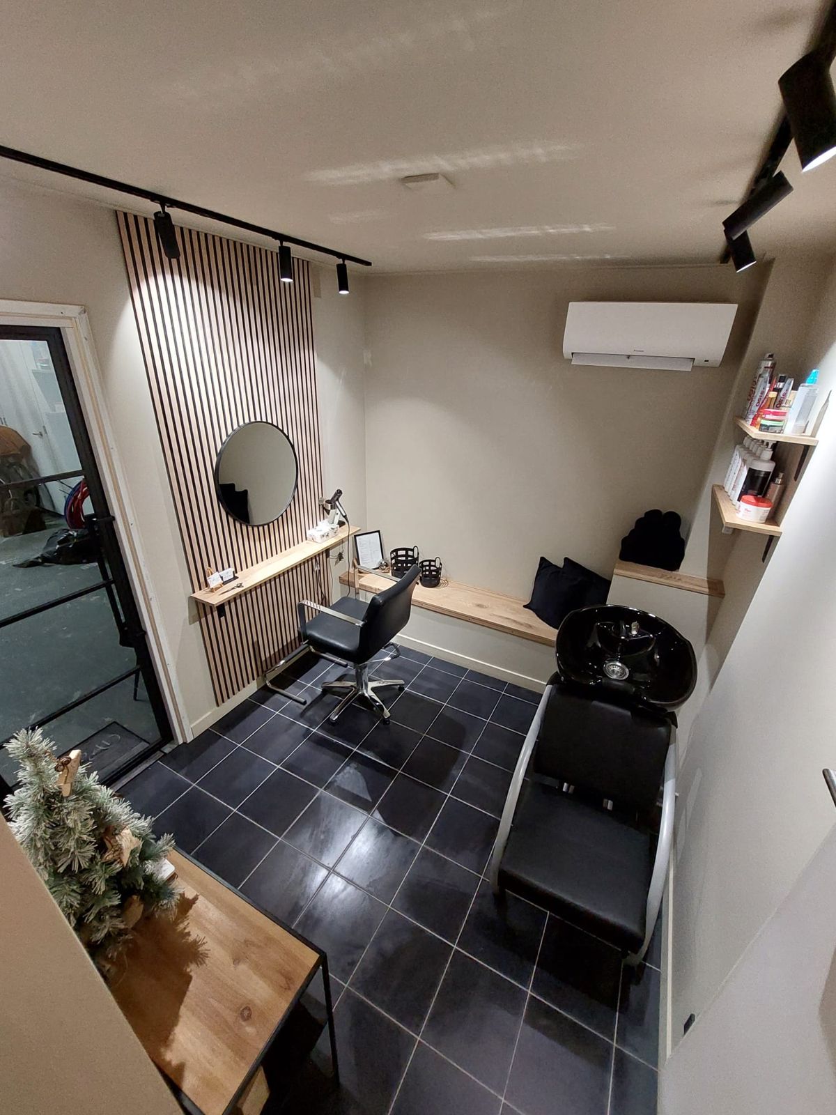 Overzicht van de salon met de kappersstoel, de wasstoel en de houten plank